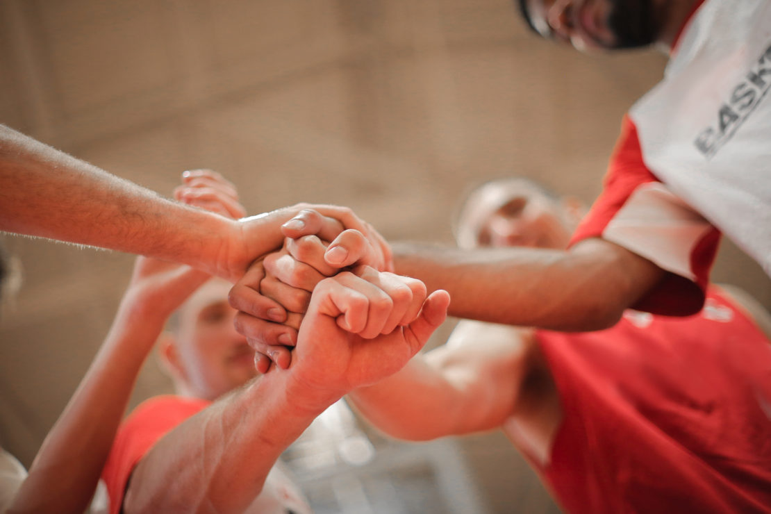 Canva - Basketball team stacking hands together